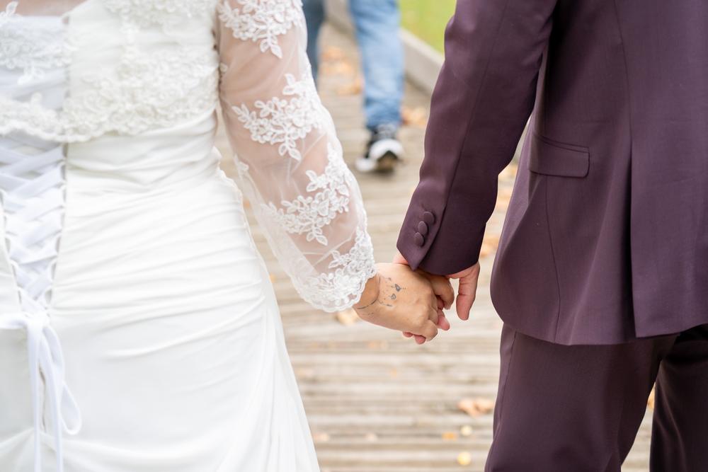 Novios de la mano, de espaldas, con el encaje de la manga del vestido, en una boda en Bilbao.