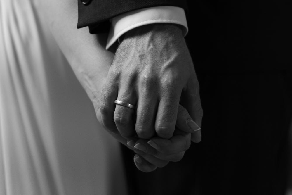 Manos de los novios entrelazadas con la alianza, en blanco y negro, boda en Hernani.