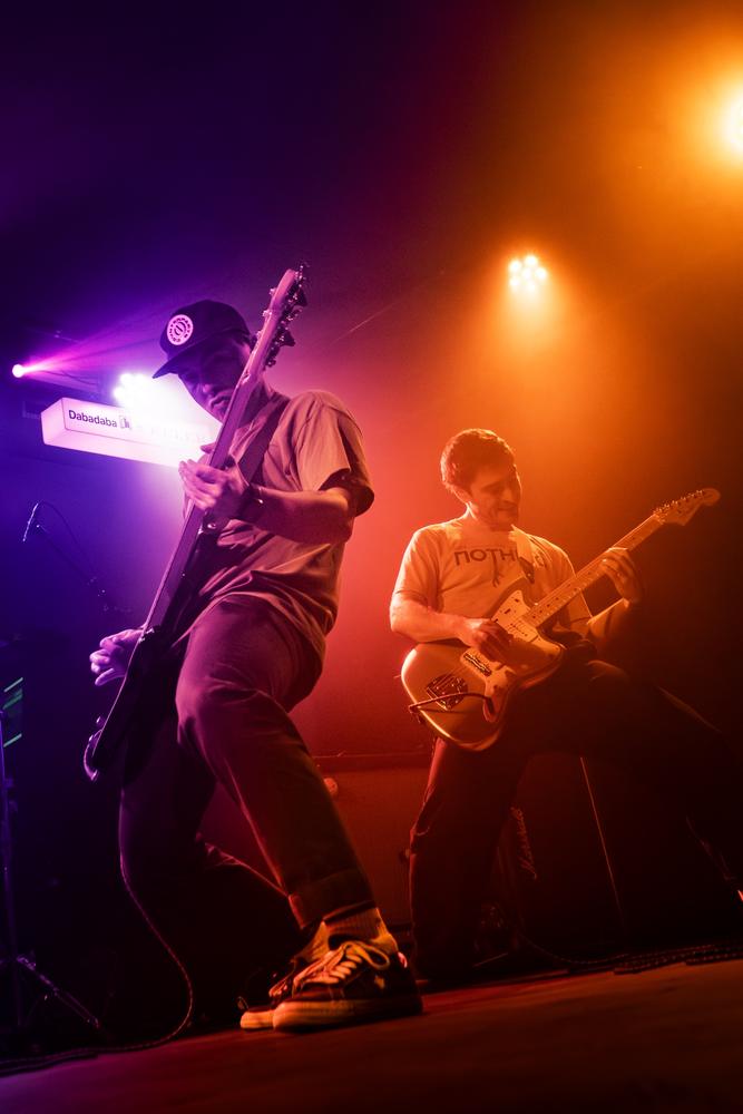 Dos guitarristas de Superlore sobre el escenario, con luces moradas y naranjas, en Donostia.
